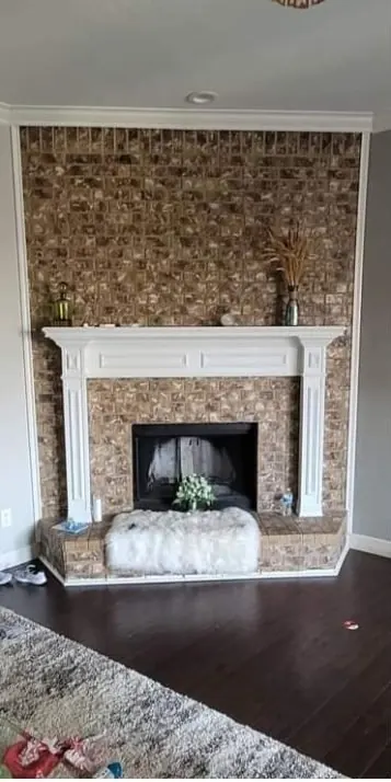 Before: Red brick fireplace refaced in stacked stone with a wood mantel