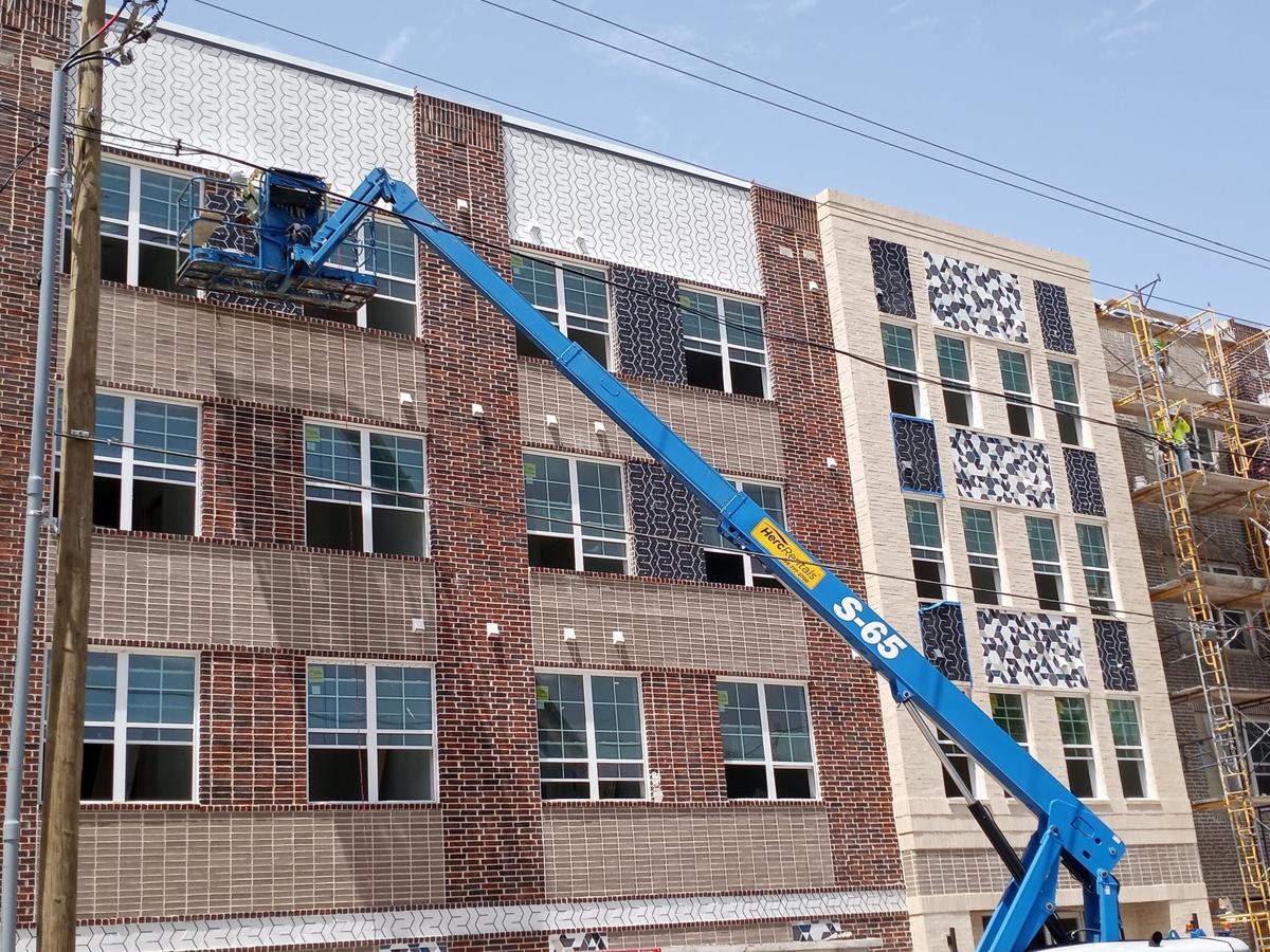 Exterior tile being installed from a boom lift