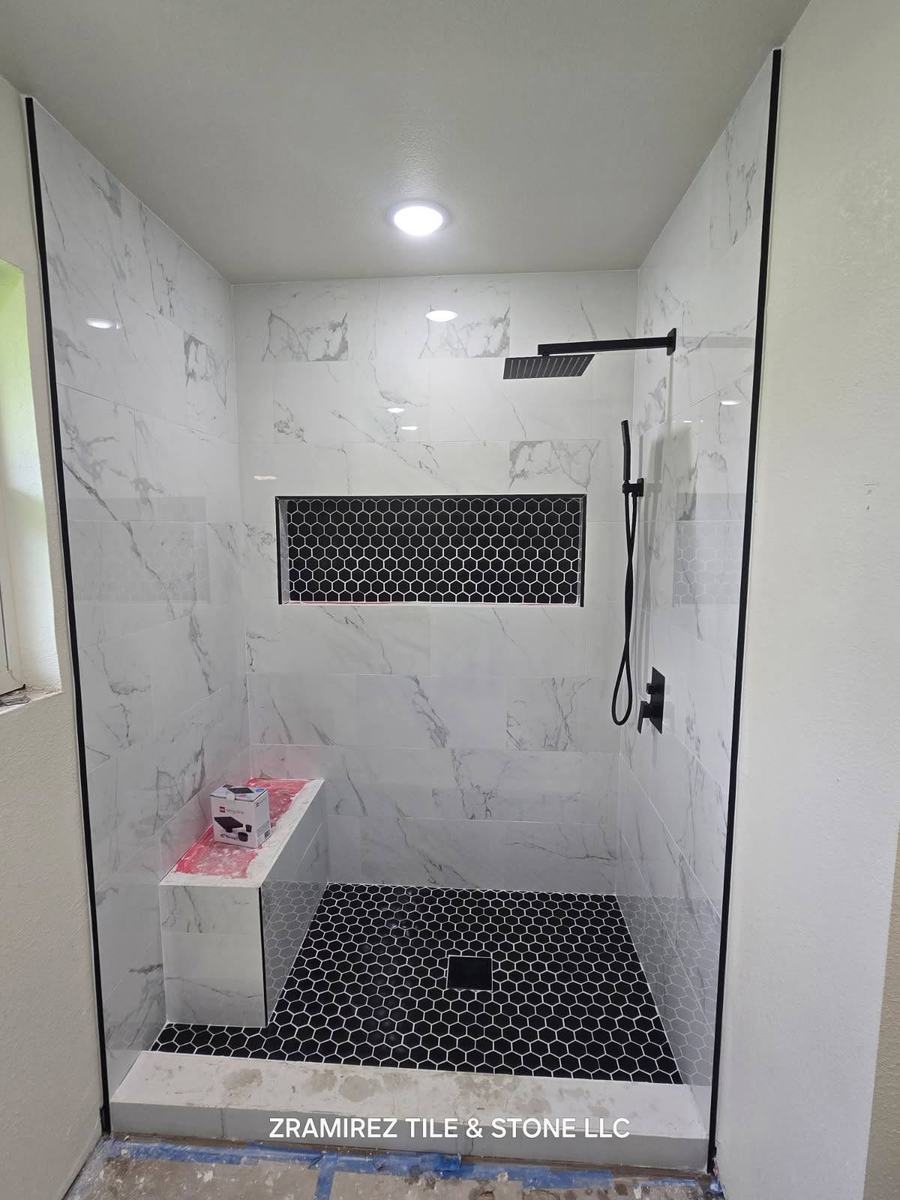 Walk-in shower with black hex floor and niche