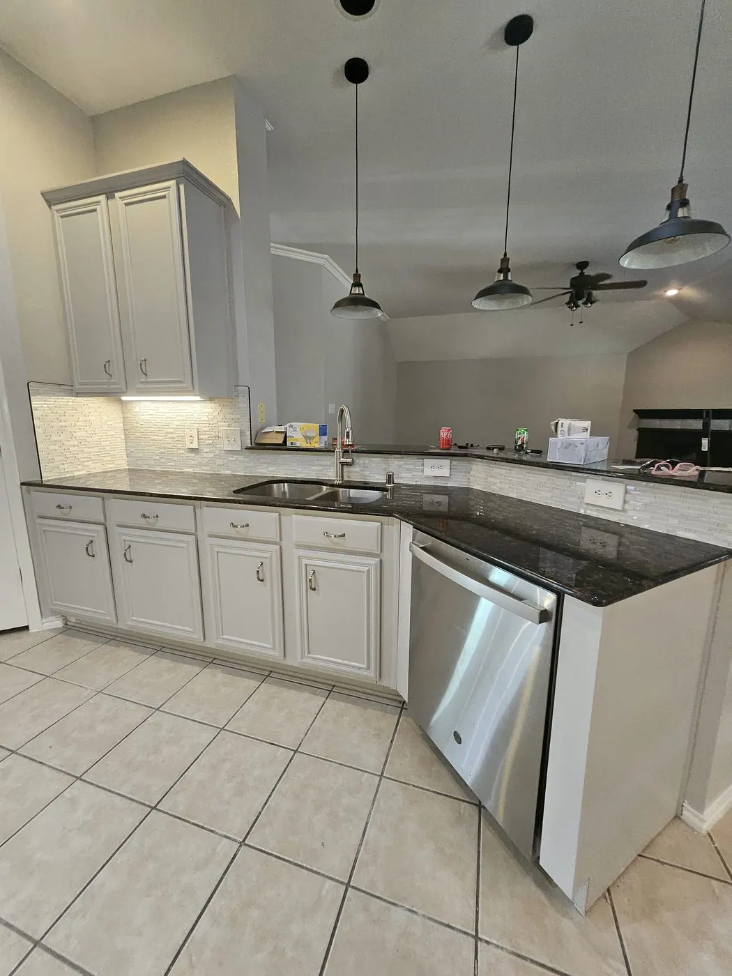 Kitchen with grey cabinets, dark granite and a white linear backsplash