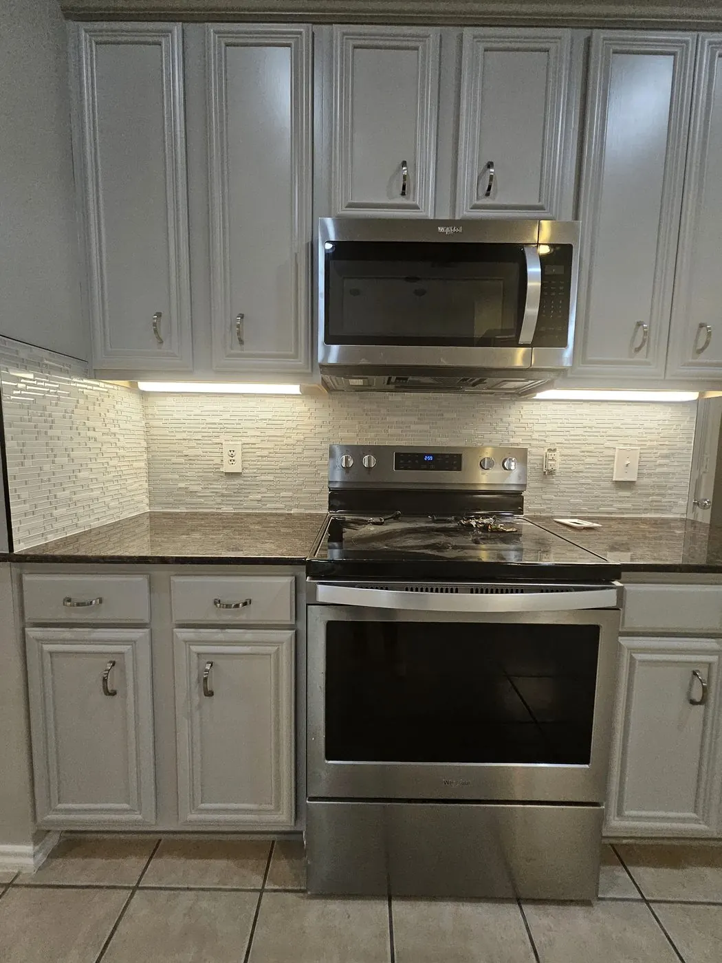 White linear backsplash behind the range, with granite counters