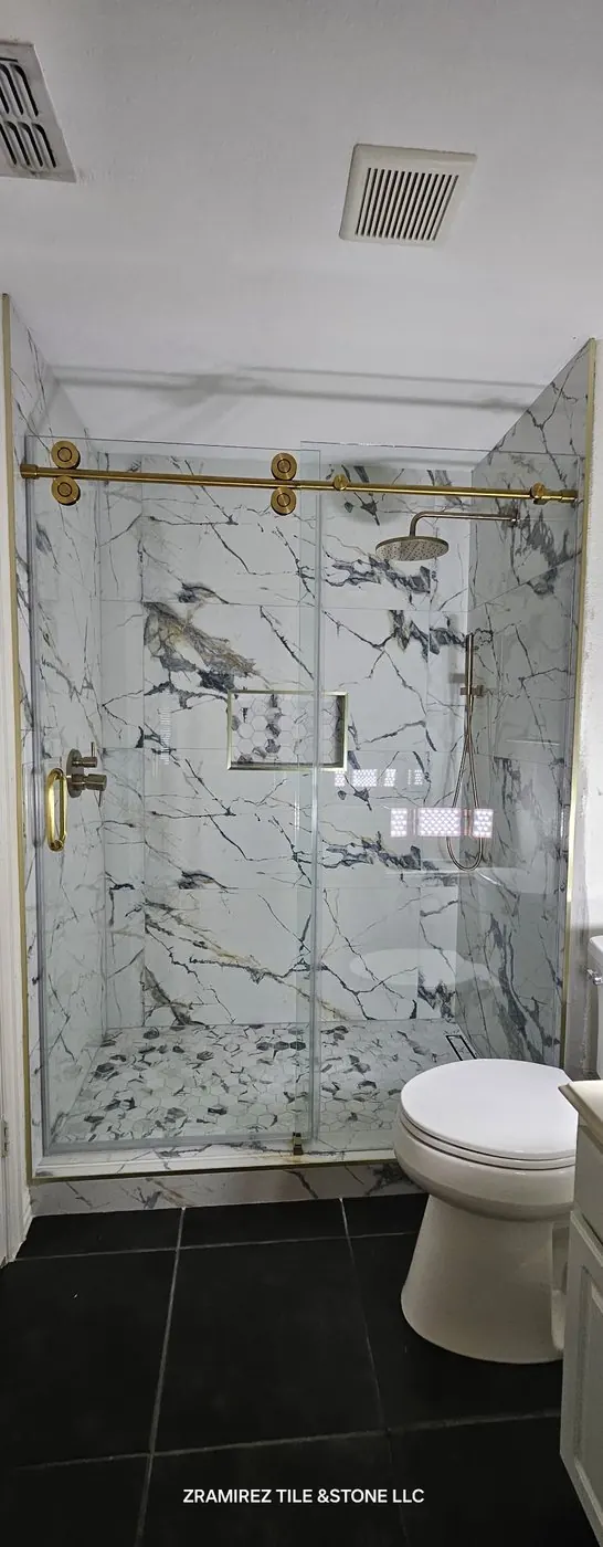 Marble-look shower with hex mosaic floor, linear drain and brushed-gold fixtures