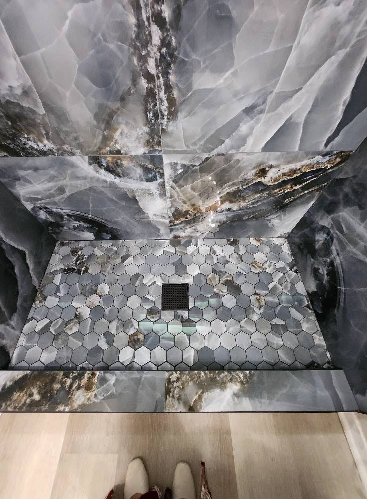 Marble-look shower with a hexagon mosaic floor and recessed niche