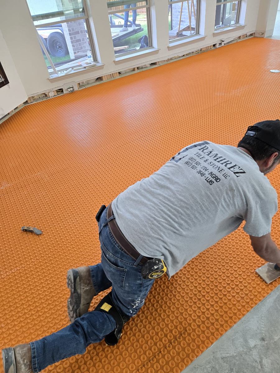 Installer laying uncoupling membrane before tiling a floor