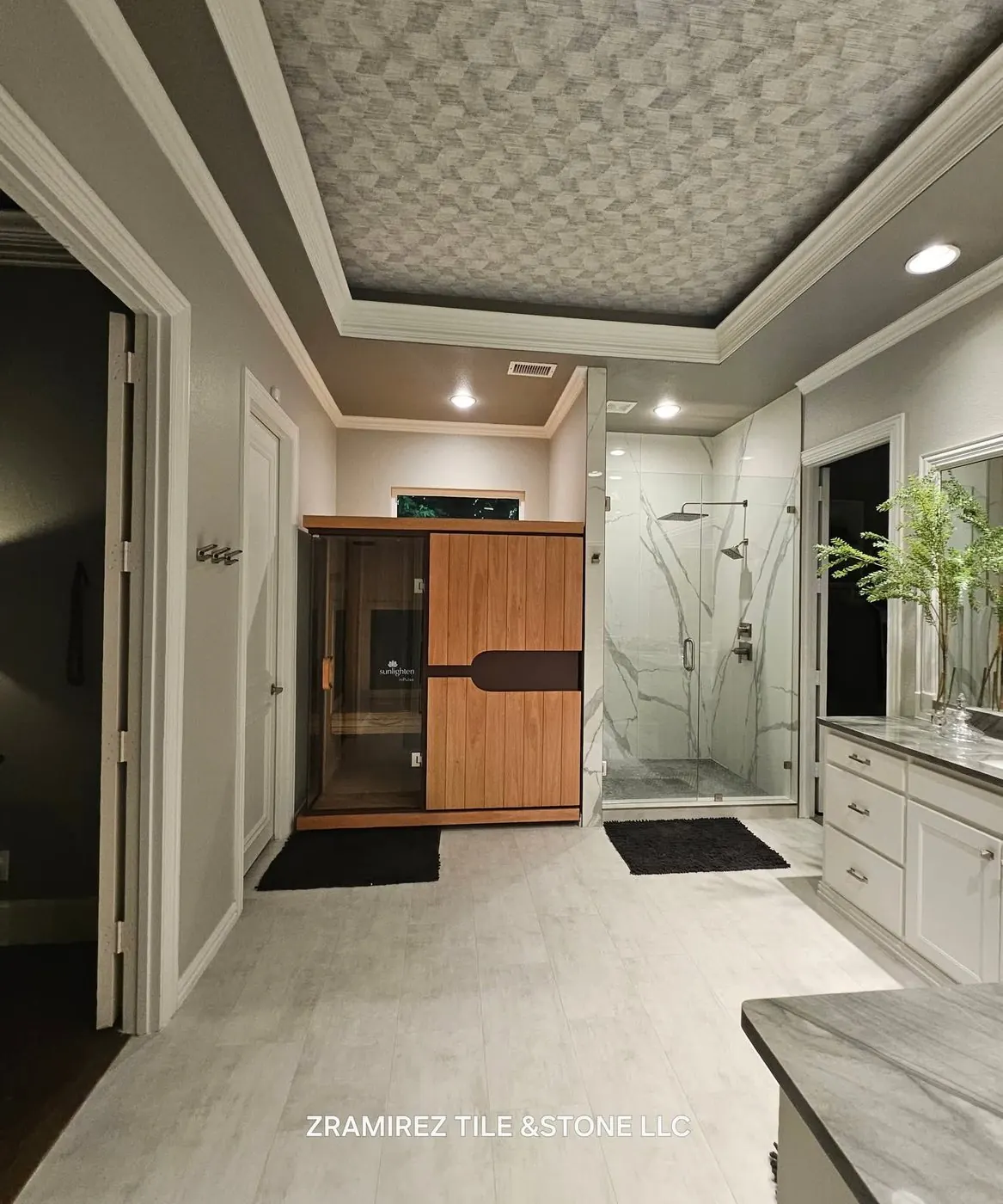 Primary bathroom: dated travertine and a drop-in tub, remodeled with a marble-look walk-in shower, new floor and an infrared sauna we installed