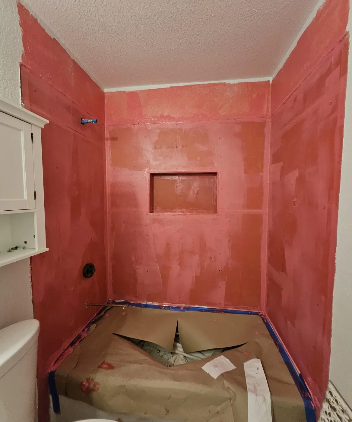 Shower walls and pan coated in red waterproofing membrane