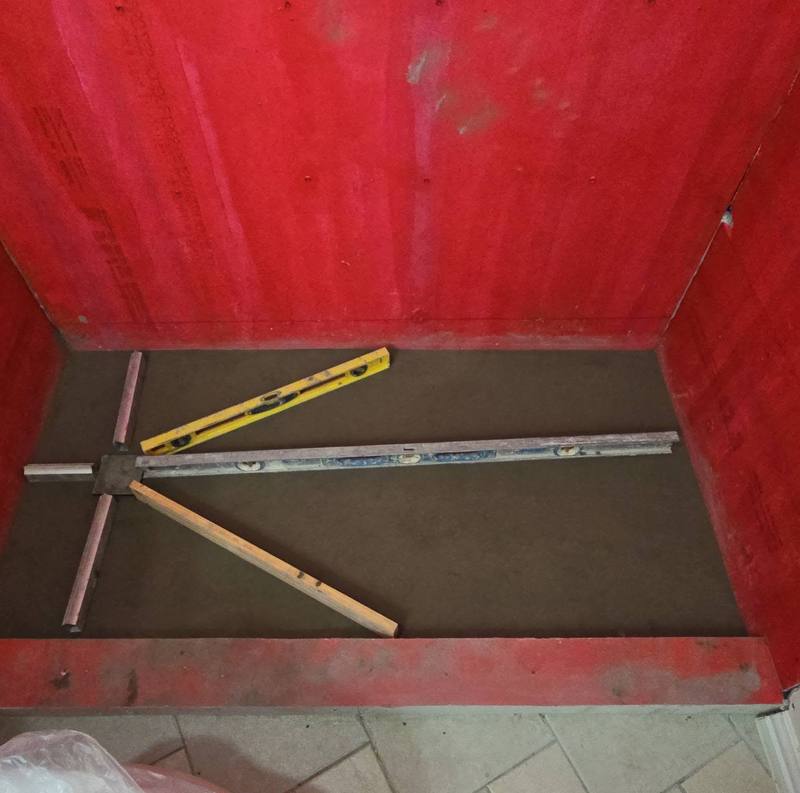 Shower walls coated in waterproofing membrane above a sloped shower pan