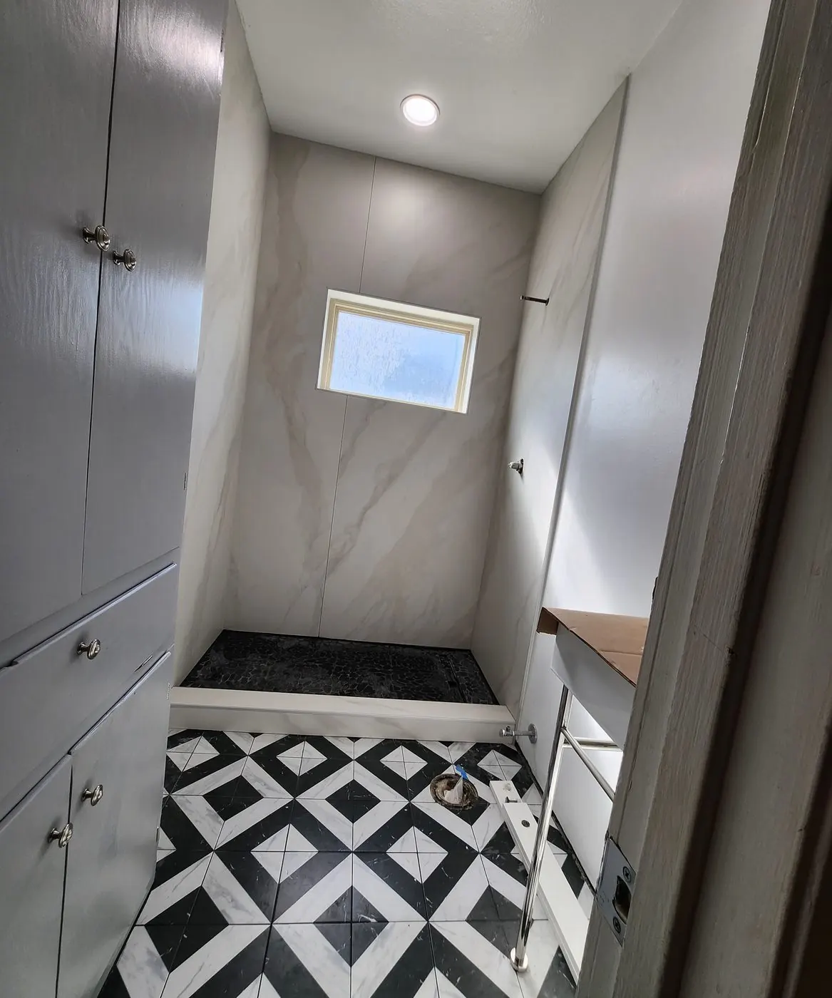 Marble-look slab shower with a black-and-white diamond floor