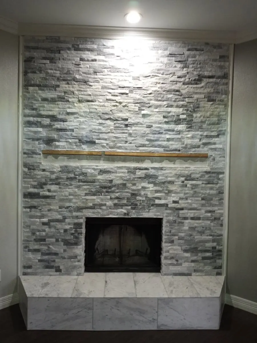 Red brick fireplace refaced in stacked stone with a wood mantel