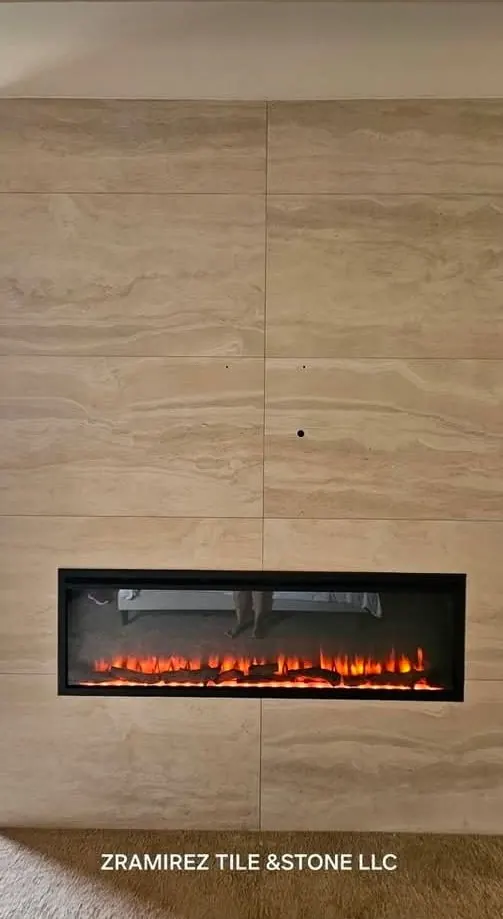 Travertine-look porcelain wall framing a linear fireplace