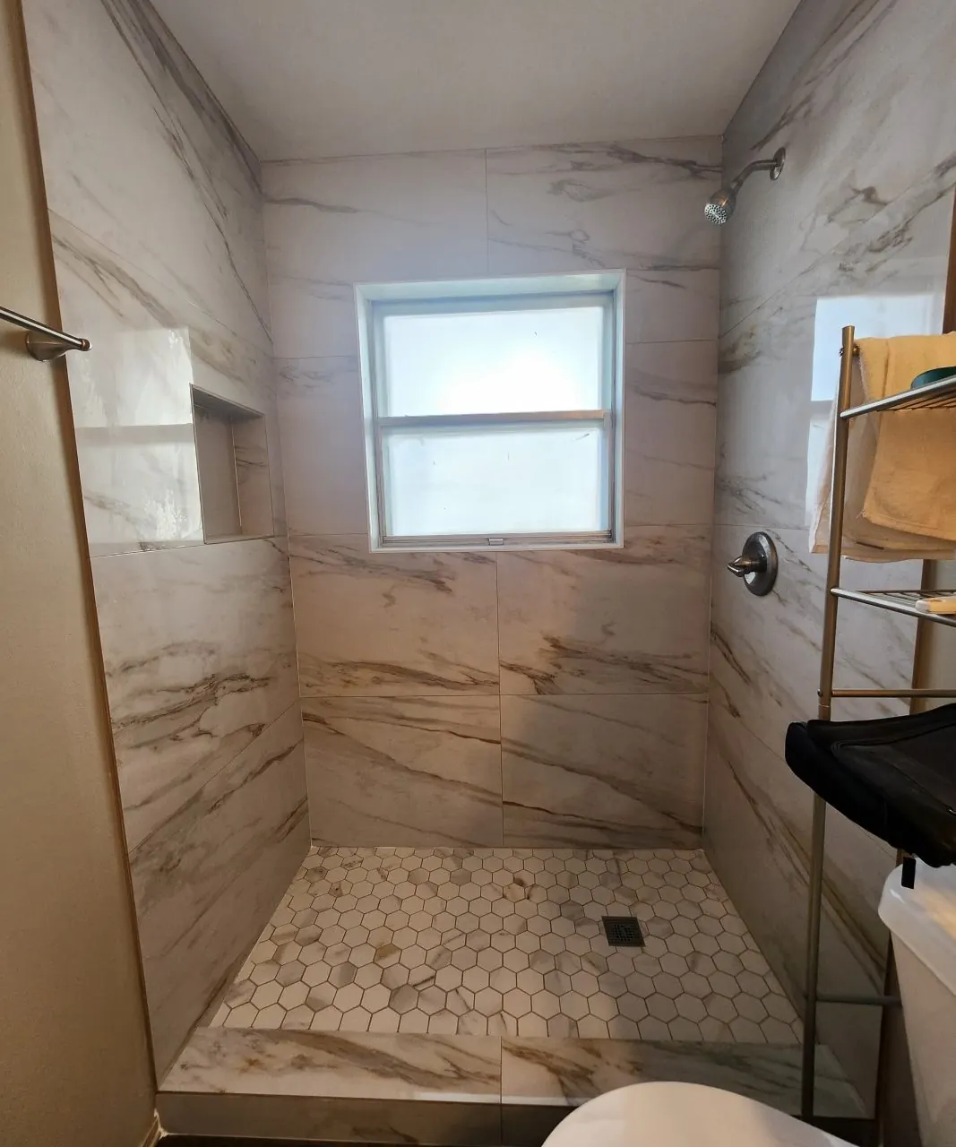 After: Acrylic tub surround replaced with a marble-look walk-in shower and hex mosaic floor