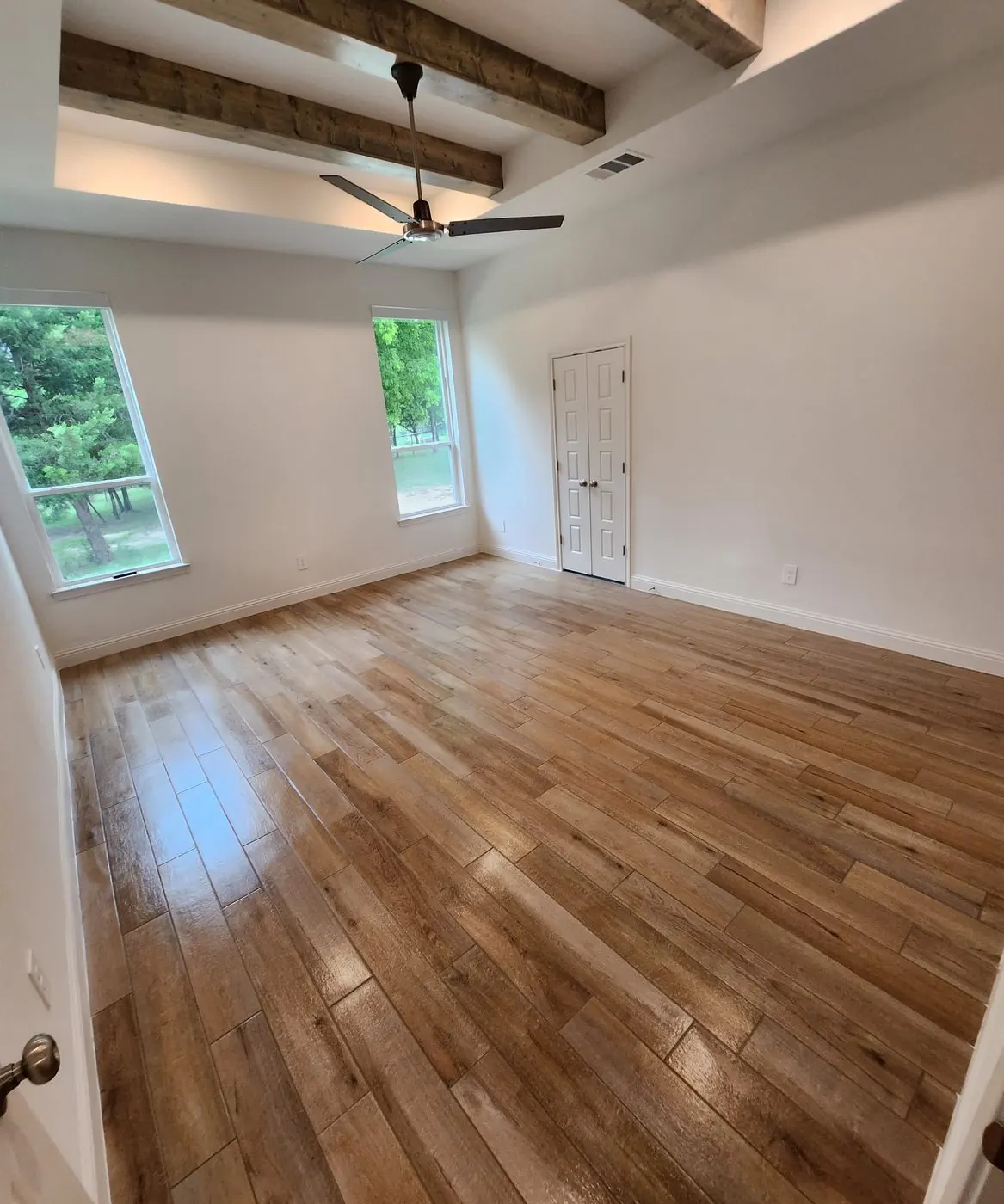 Wood-look plank tile in a bedroom with ceiling beams